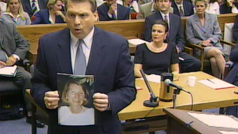 A man holds a photo as he addresses the court.